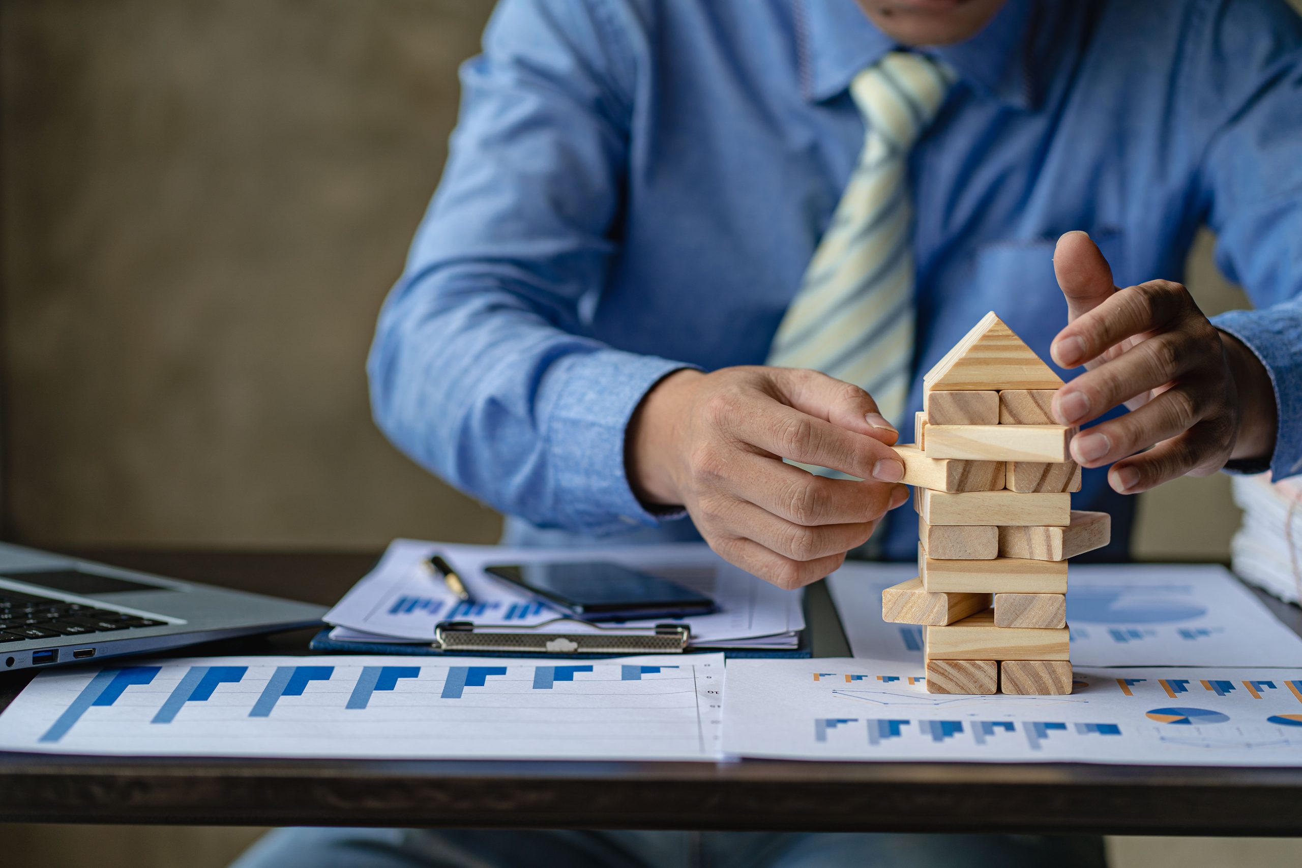 Businessman working with showing business graph Business expansion and growth plan With wooden block tower next to it with direction of growth and success, property and real estate insurance concept