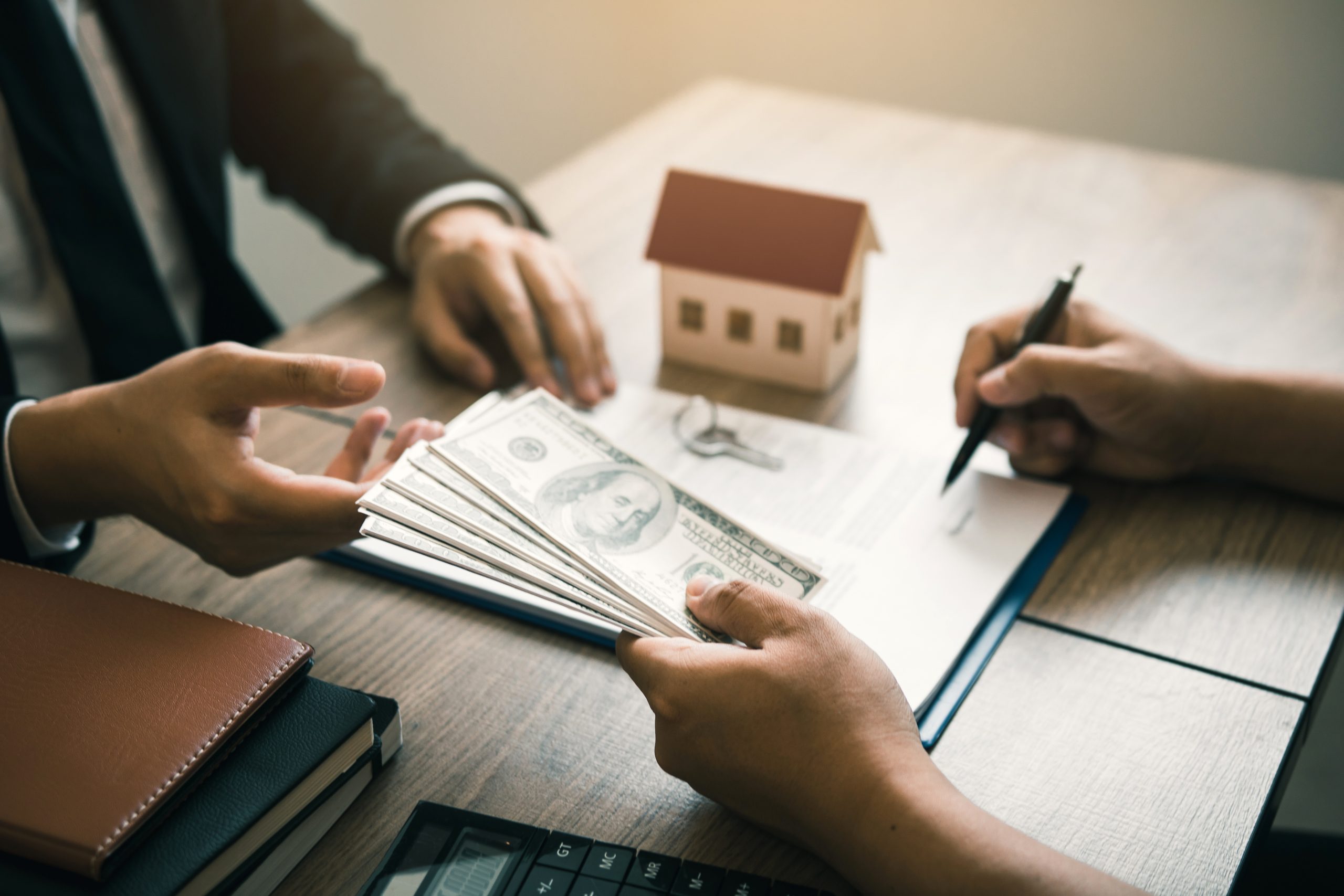 Investors are using st pen on the contract paper about buying a new home while filing cash as a deposit for the agent.